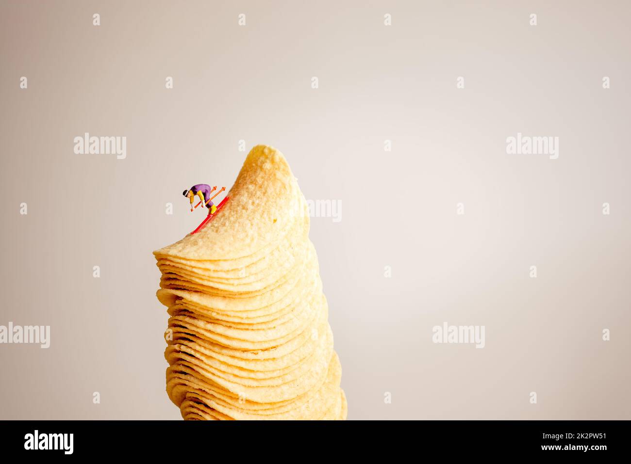 Skieur miniature en glissant sur la pile de croustilles de pommes de terre Banque D'Images