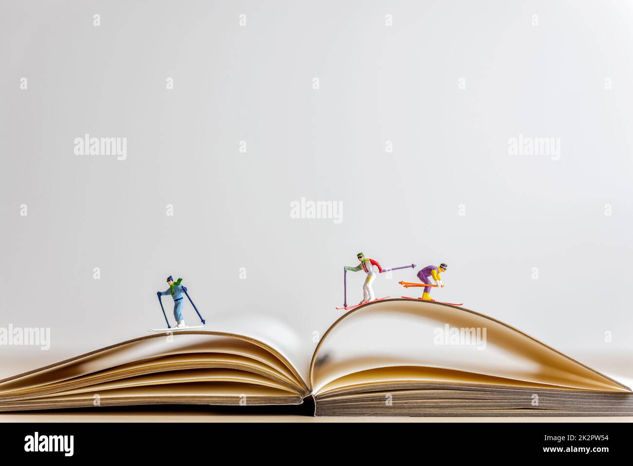 Les skieurs miniatures glissent vers le bas du livre ouvert Banque D'Images