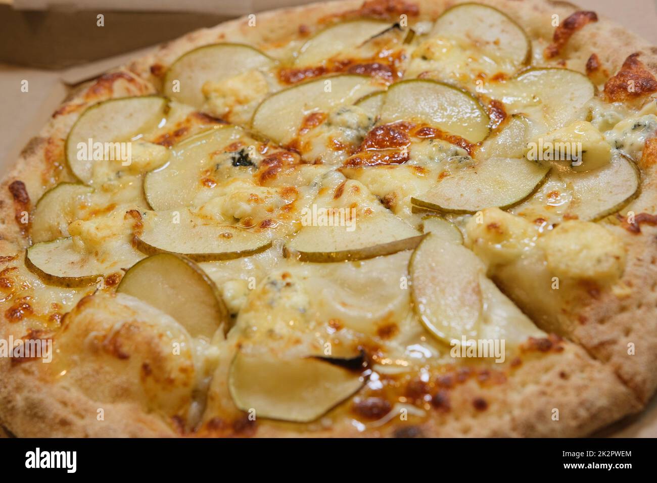 Pizza en tranches avec poire, gorgonzola et miel en nid d'abeille sur le papier à pâtisserie vue latérale Banque D'Images