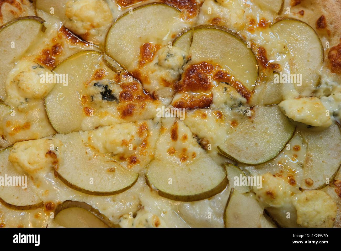 Pizza en tranches avec poire, gorgonzola et miel en nid d'abeille sur papier à pâtisserie vue de dessus, gros plan Banque D'Images
