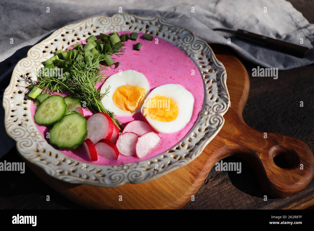 Soupe froide de betteraves avec œuf, concombre, pommes de terre et légumes verts sur la table en bois. Spécialité pour les journées chaudes. Faible profondeur de champ, mise au point sélective Banque D'Images