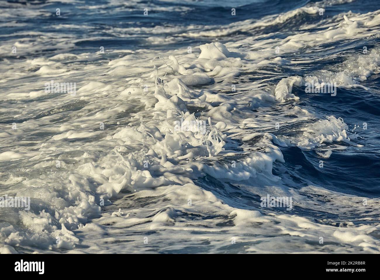 Splasing avec de la mousse des vagues dans l'eau de mer Banque D'Images