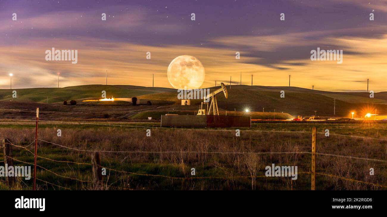 Une vue magnifique sur une immense pleine lune dans un ciel violet-or avec des étoiles brillantes sur une colline dans la campagne Banque D'Images