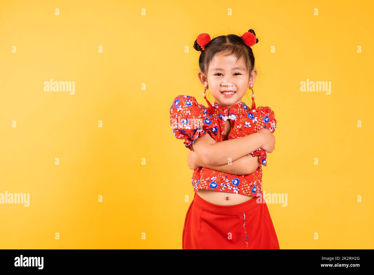 Joyeux asiatique chinois petite fille sourire porter le cheongsam rouge bras croisés Banque D'Images