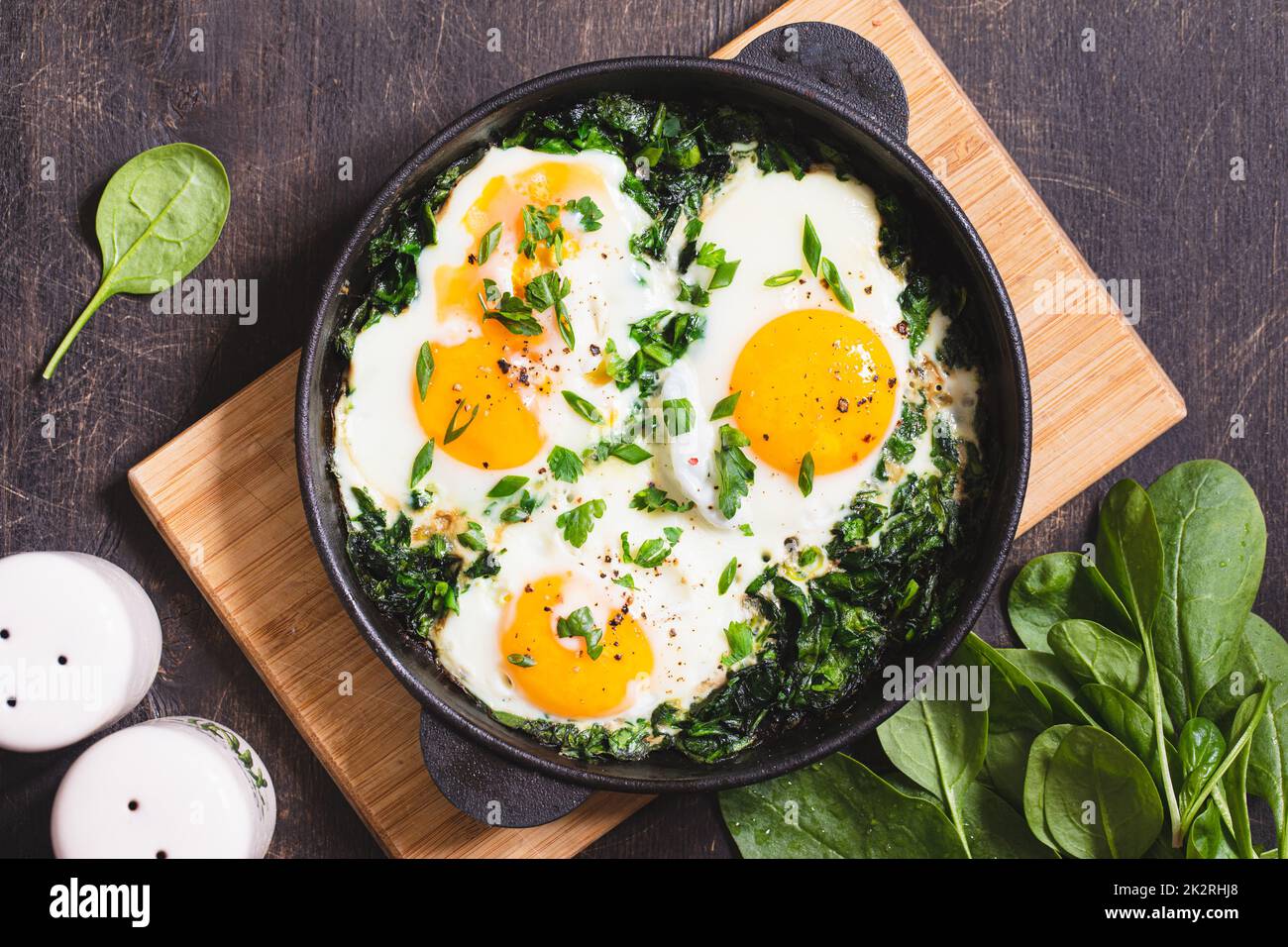 shakshuka vert dans une poêle en fonte. œufs frits aux épinards et toasts frits. petit déjeuner sain et nutritif Banque D'Images