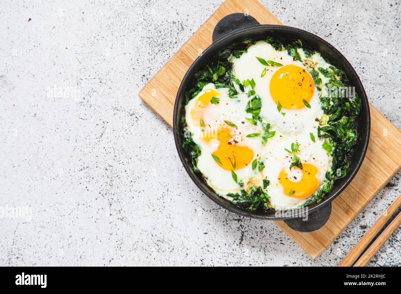 shakshuka vert dans une poêle en fonte. œufs frits aux épinards et toasts frits. petit déjeuner sain et nutritif Banque D'Images