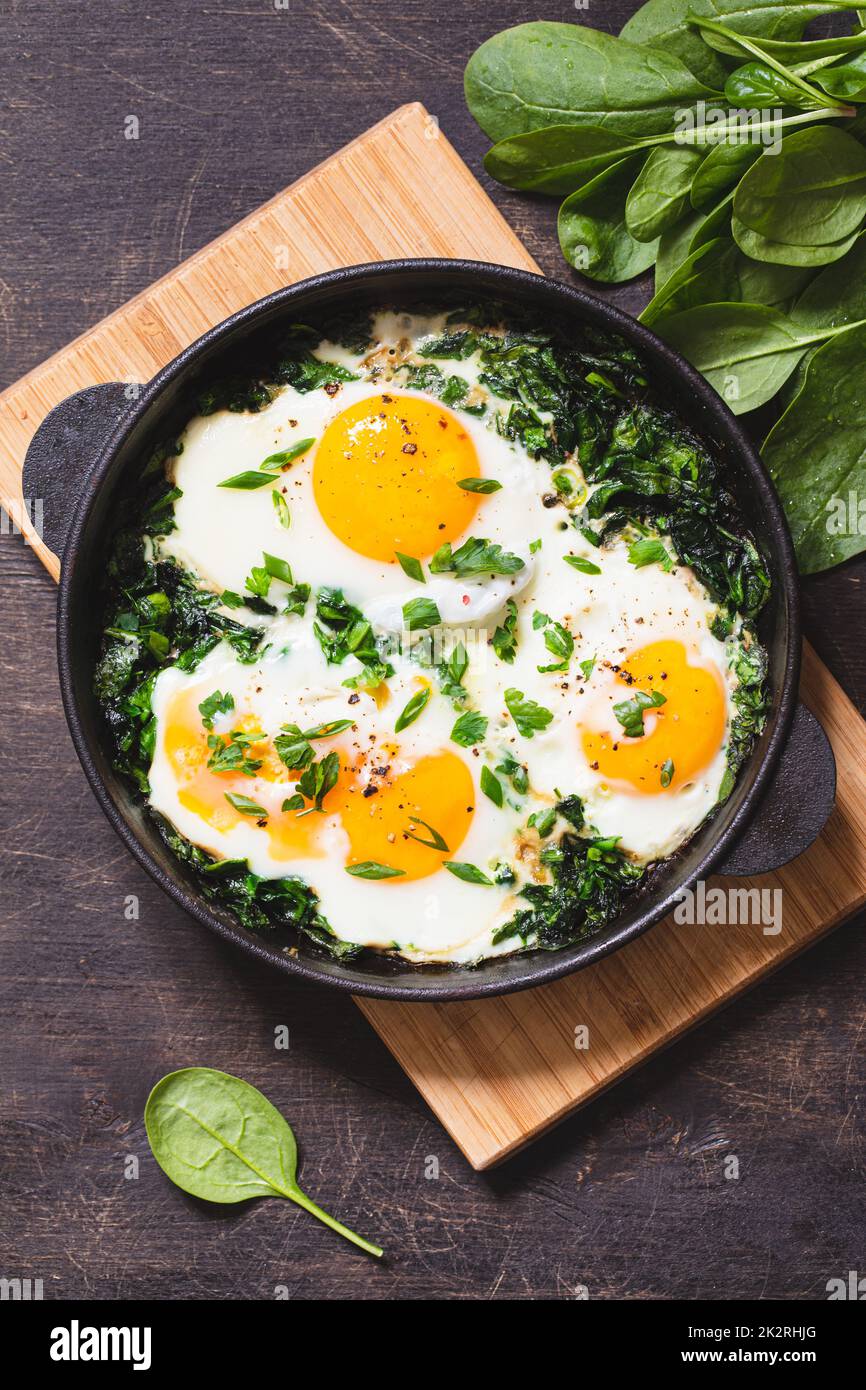 shakshuka vert dans une poêle en fonte. œufs frits aux épinards et toasts frits. petit déjeuner sain et nutritif Banque D'Images