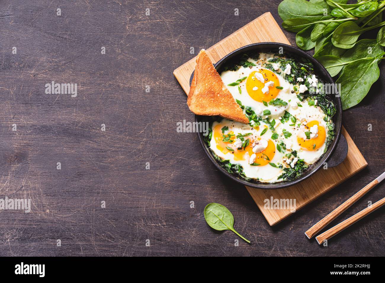 shakshuka vert dans une poêle en fonte. œufs frits aux épinards et toasts frits. petit déjeuner sain et nutritif Banque D'Images