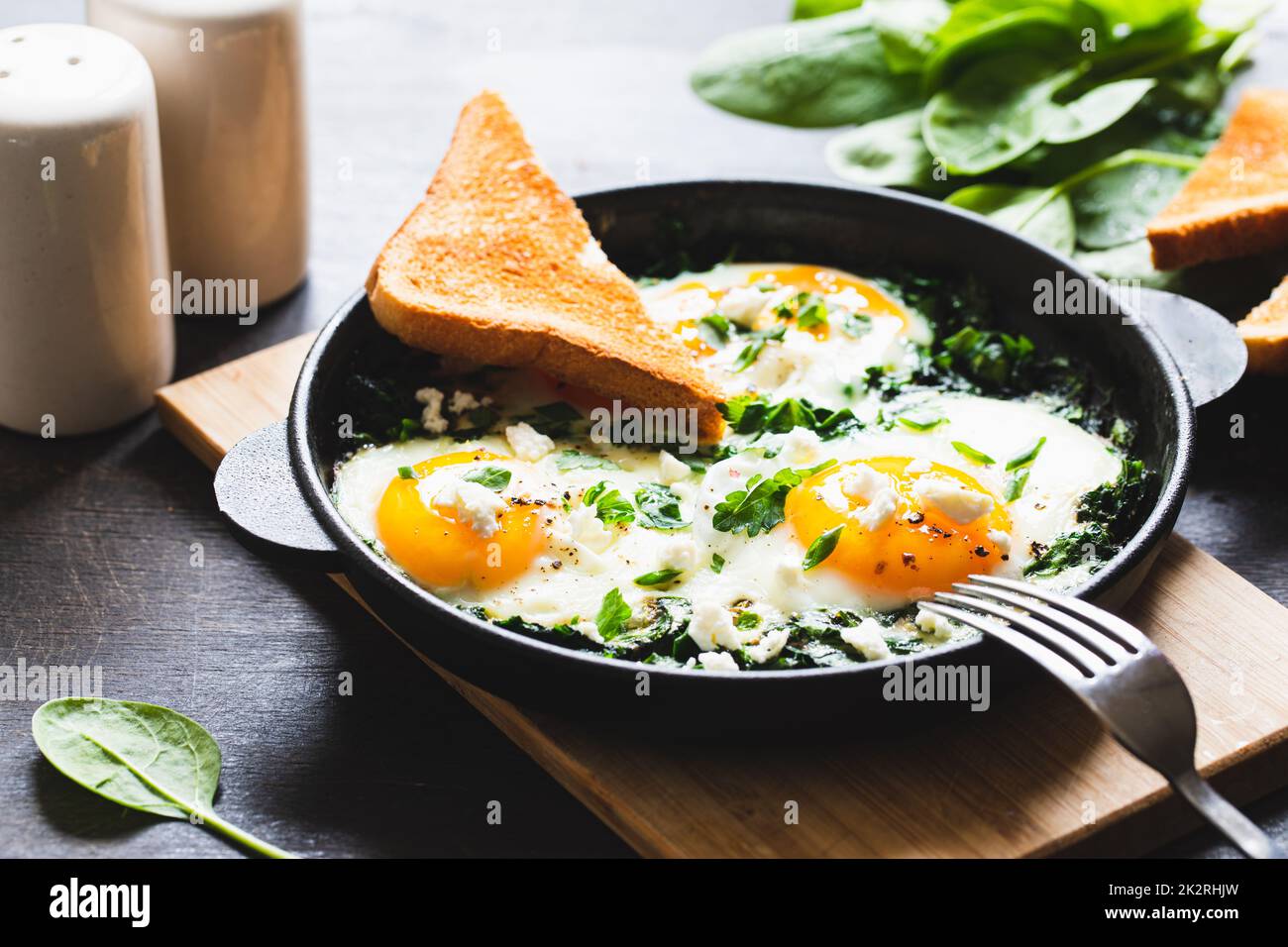 shakshuka vert dans une poêle en fonte. œufs frits aux épinards et toasts frits. petit déjeuner sain et nutritif Banque D'Images