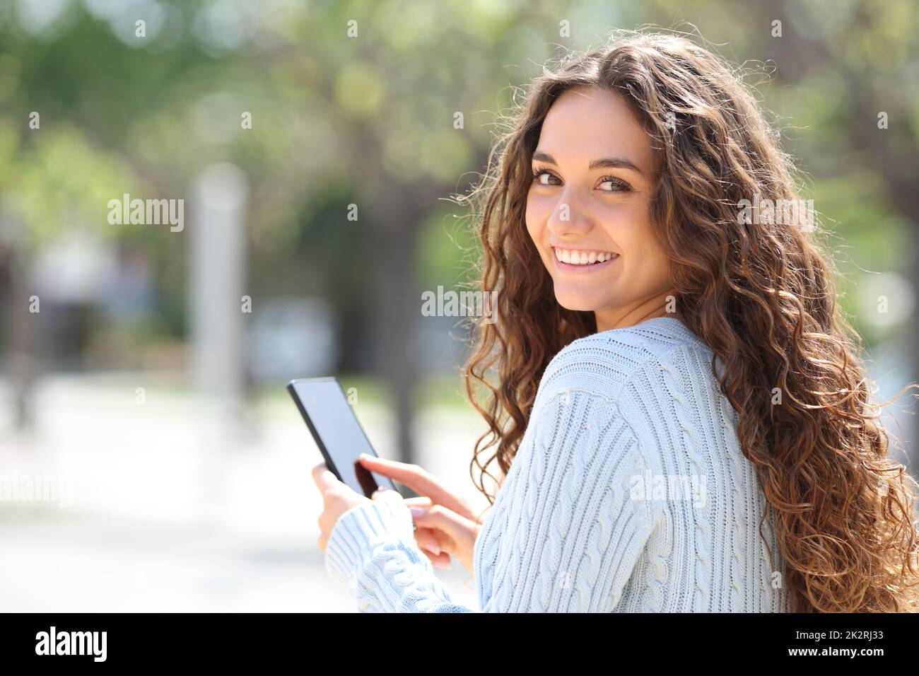 Bonne femme utilisant un smartphone qui vous regarde à l'extérieur Banque D'Images