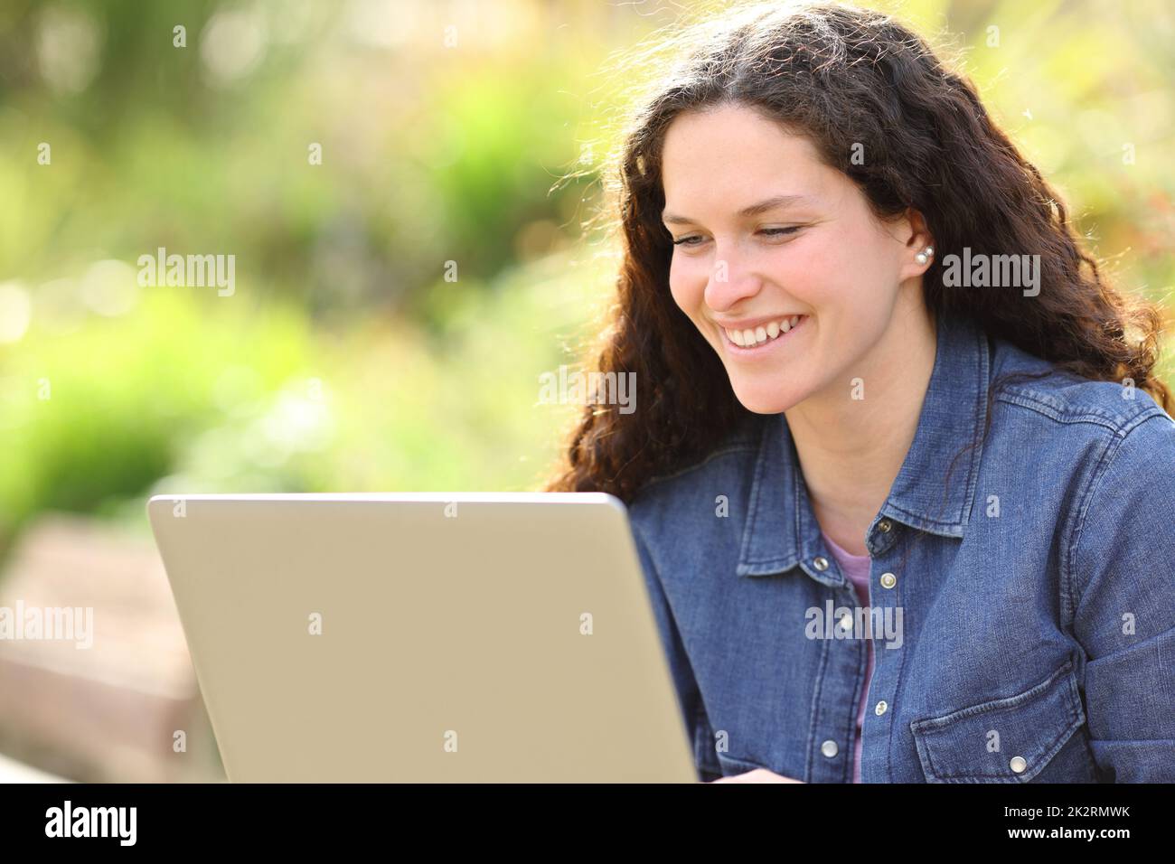 Bonne femme utilisant un ordinateur portable dans un parc Banque D'Images