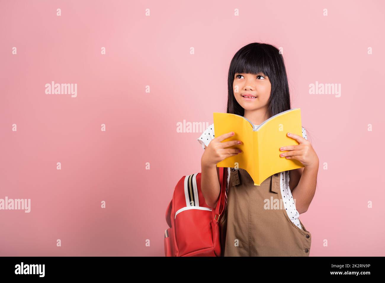 Petit enfant asiatique de 10 ans tenant et lisant un livre jaune Banque D'Images