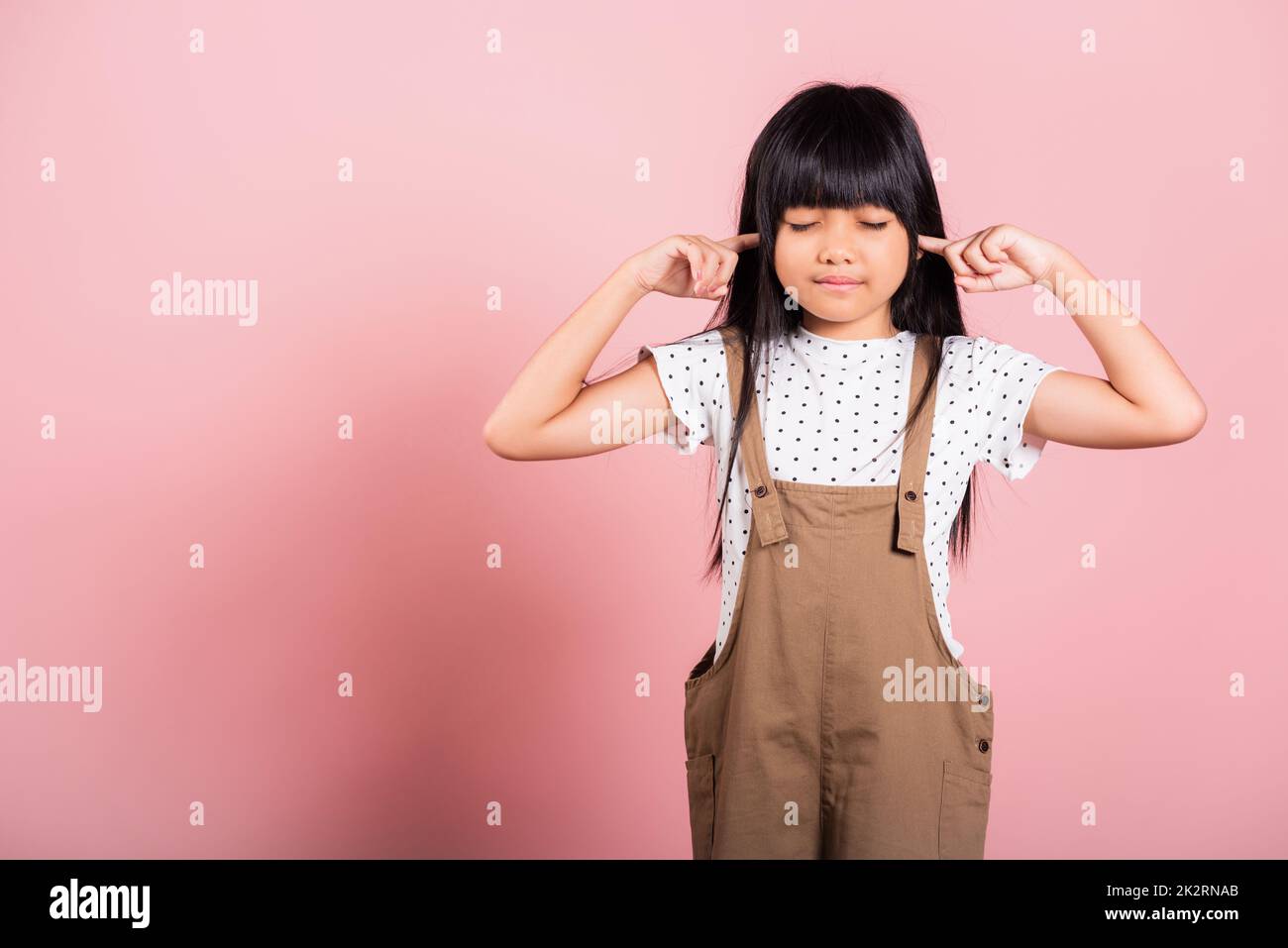 Petit enfant asiatique de 10 ans Fermez ses oreilles avec les doigts et les yeux Banque D'Images