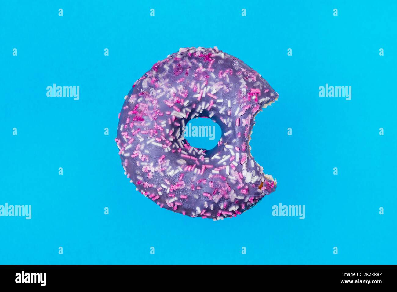 Piquer un donut glacé avec des arrosettes colorées sur un fond bleu Banque D'Images