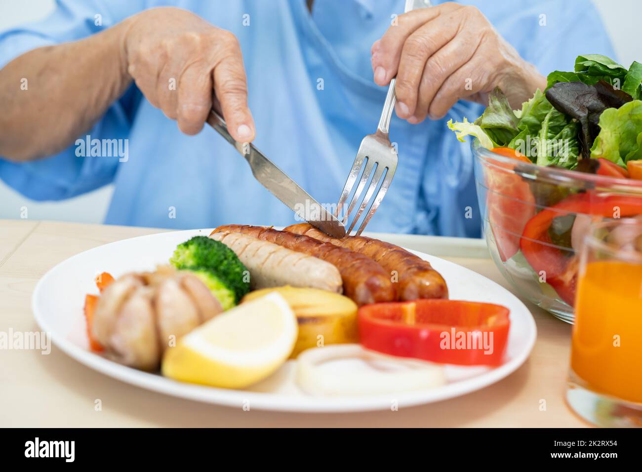 Asiatique senior ou âgée vieille femme patient de manger le petit déjeuner et légumes saine alimentation avec espoir et heureux tout en étant assis et faim sur le lit à l'hôpital. Banque D'Images