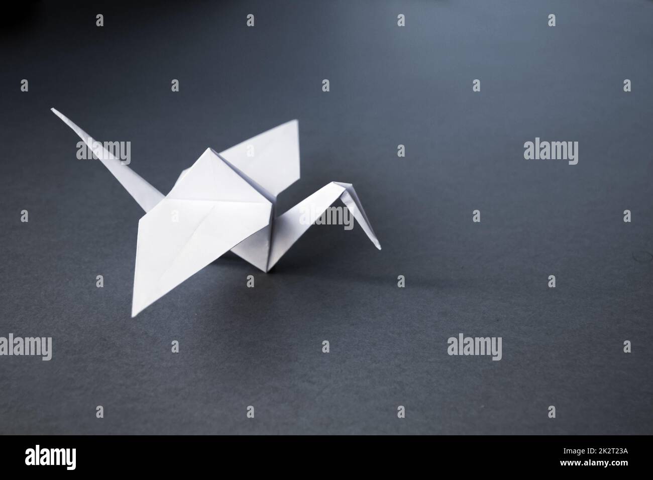 Grue à papier blanc origami isolé sur fond gris Banque D'Images
