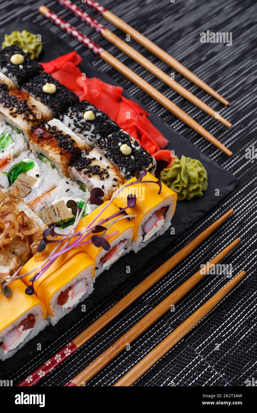 Différents types de sushis servis sur une assiette en pierre dans un restaurant. Magnifique décor et service avec baguettes Banque D'Images