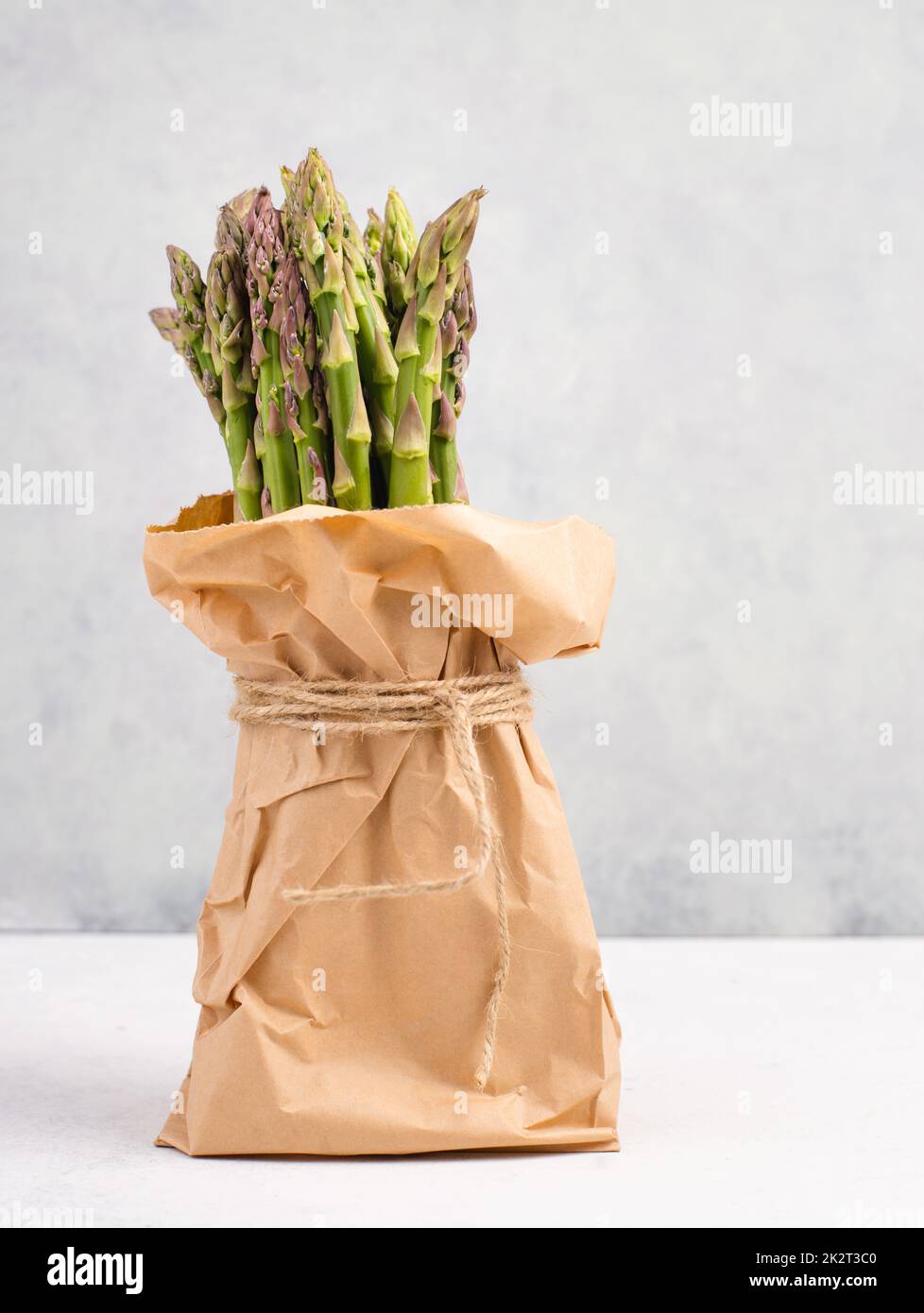 Bouquet d'asperges vert frais sur une table texturée blanche, légumes au printemps, cuisine gastronomique, cuisine végétalienne Banque D'Images