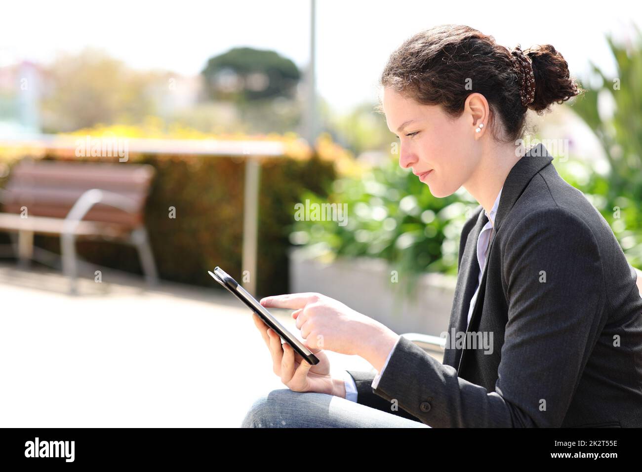 Femme d'affaires utilisant une tablette assis sur un banc Banque D'Images