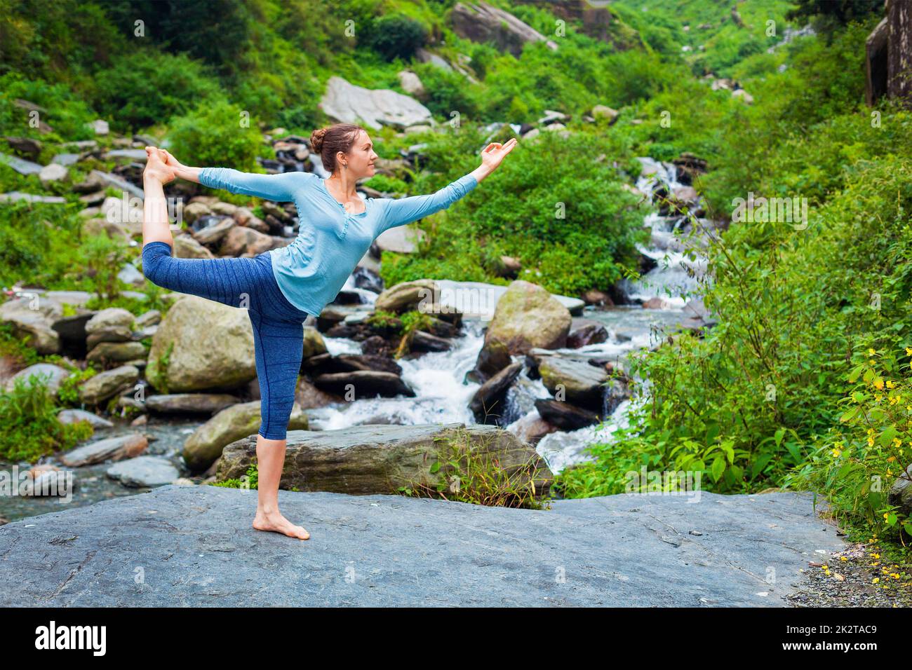 Woman doing yoga asana dehors à la cascade Banque D'Images