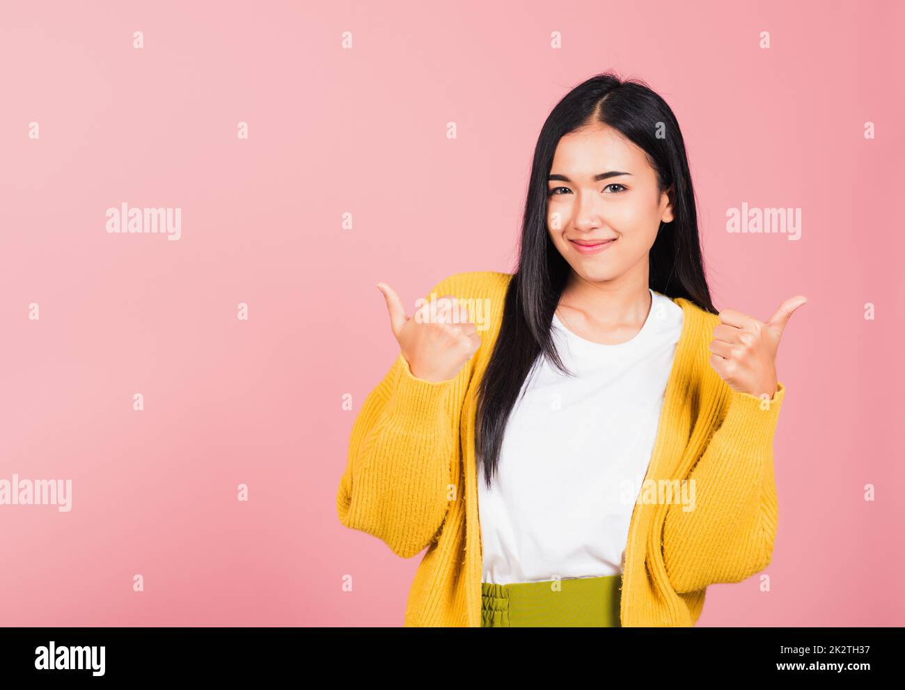 Portrait asiatique belle jeune femme sourire elle debout fait le pouce vers le haut, OK signe pour convenir studio tourné isolé sur fond rose, Thai femelle réussi comme le doigt geste avec l'espace de copie Banque D'Images