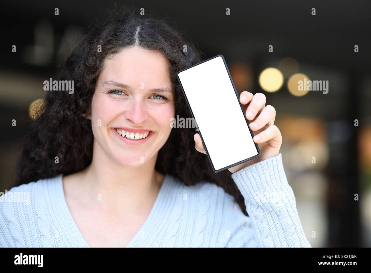 Bonne femme montrant un écran de téléphone cellulaire vide à l'appareil photo Banque D'Images