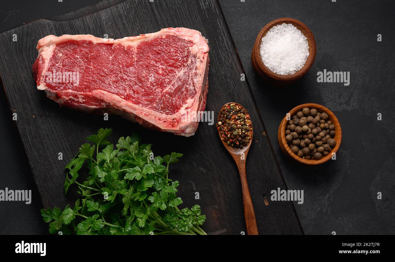 Morceau de viande de bœuf frais, steak de striploin sur fond noir, vue du dessus. Morceau de viande marbré New York Banque D'Images