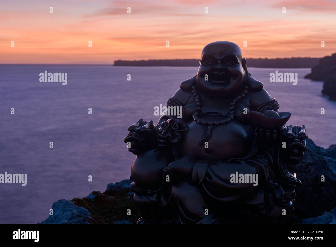 Bouddha figure sur quelques rochers, au coucher du soleil, sur la mer Banque D'Images
