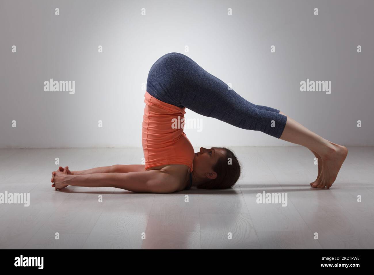Femme sportive pratique le yoga asana Halasana Banque D'Images