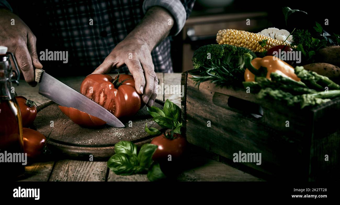 Crop man trancheuse de tomate pendant la préparation saine du dîner Banque D'Images