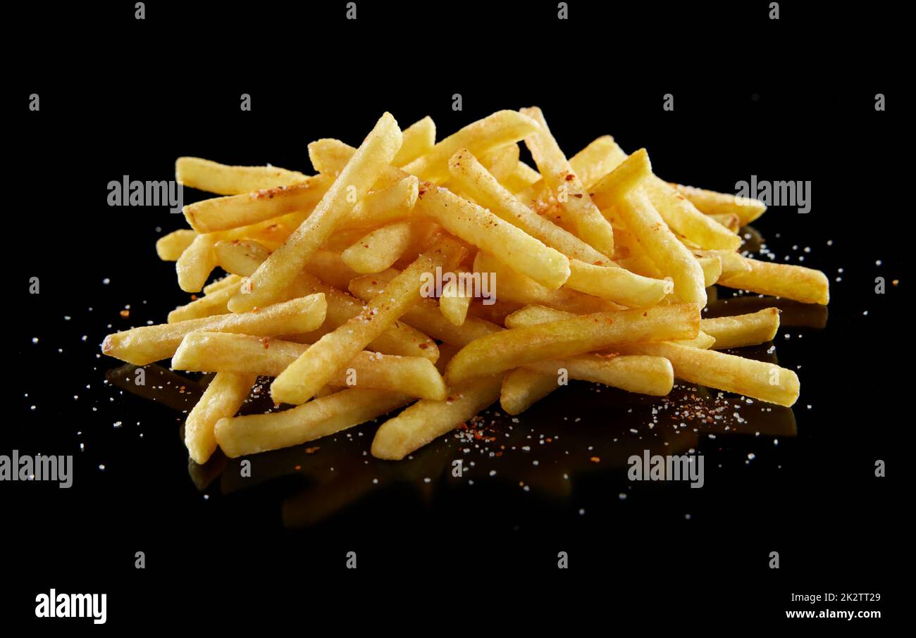 Pile de délicieuses pommes de terre frites avec sel sur fond noir Banque D'Images