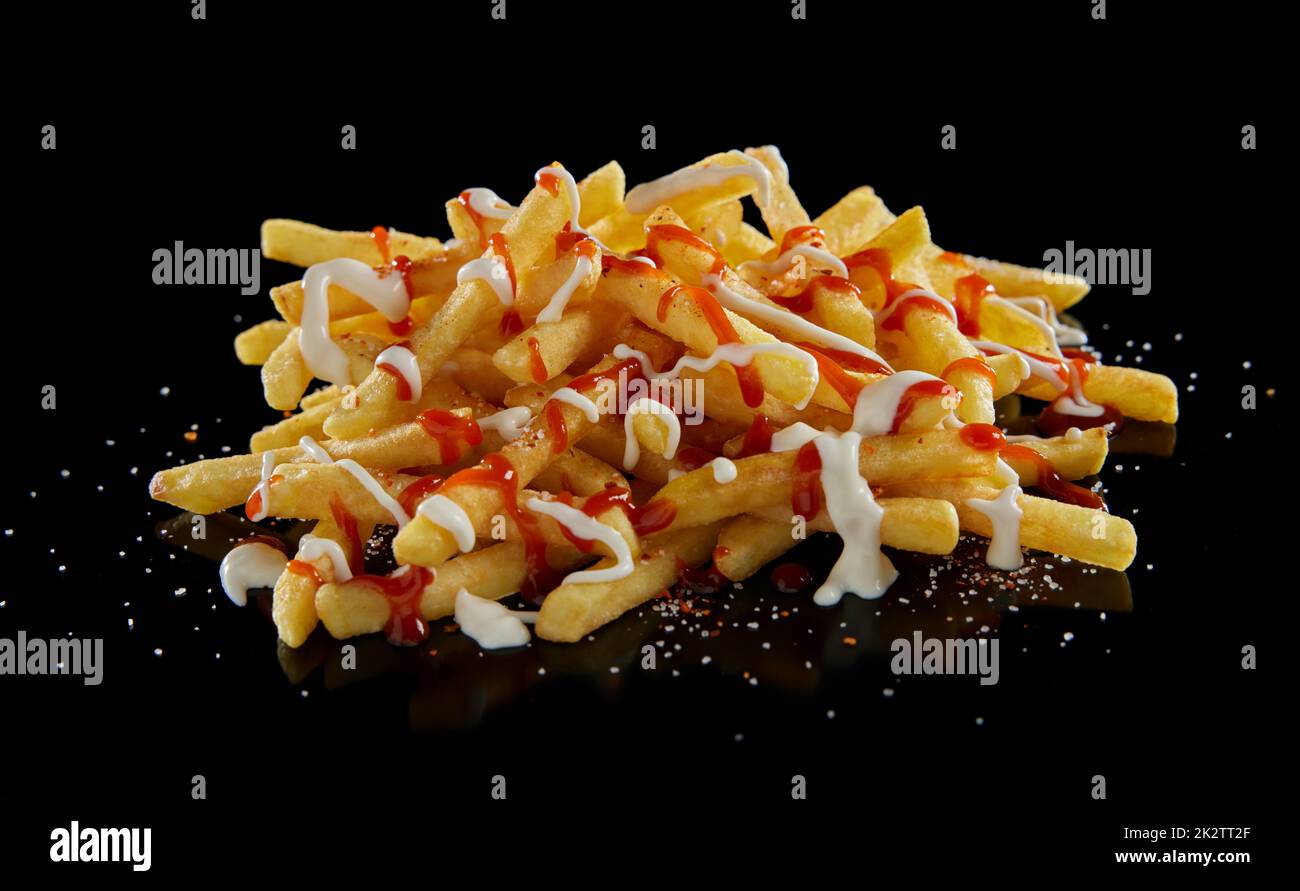Sauces blanches et rouges sur frites sur table noire Banque D'Images