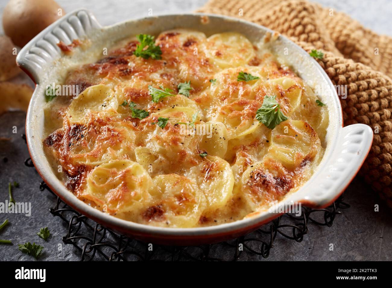 Plat en céramique de gratin de pommes de terre avec fromage râpé et persil Banque D'Images