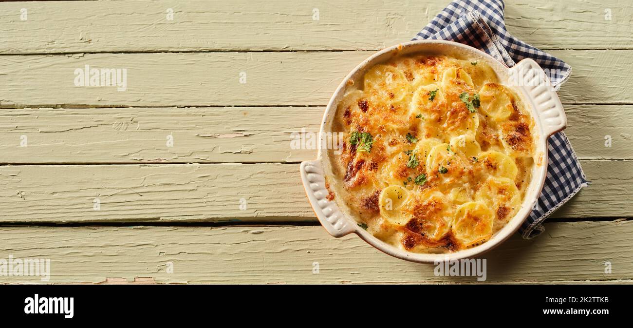 Délicieux gratin de pommes de terre dans une vaisselle en céramique sur une table en bois Banque D'Images