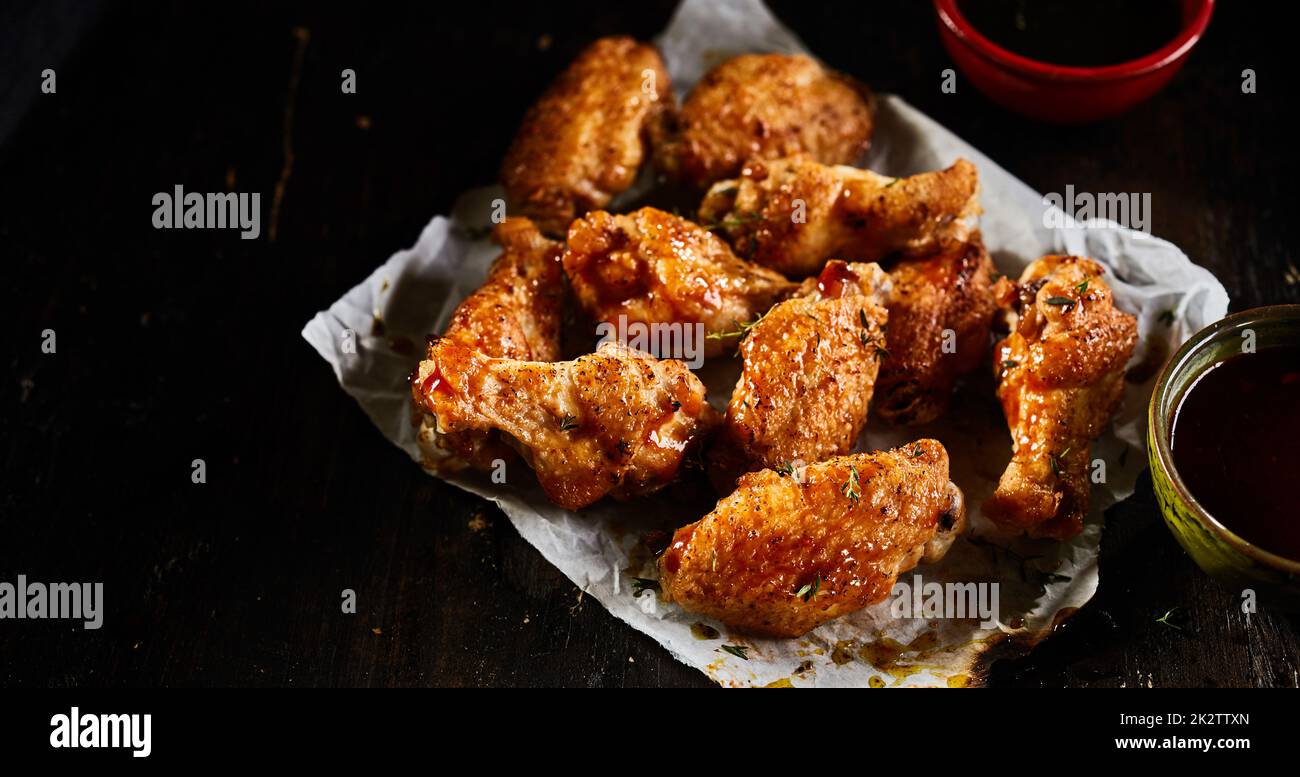 De savoureuses ailes de poulet sur une table sombre Banque D'Images
