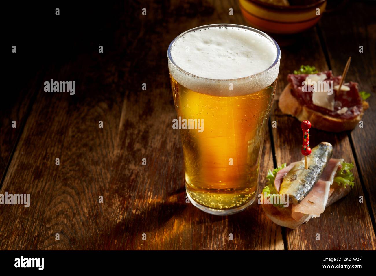 Pinte de bière pression froide dans un grand verre avec de délicieuses tapas Banque D'Images