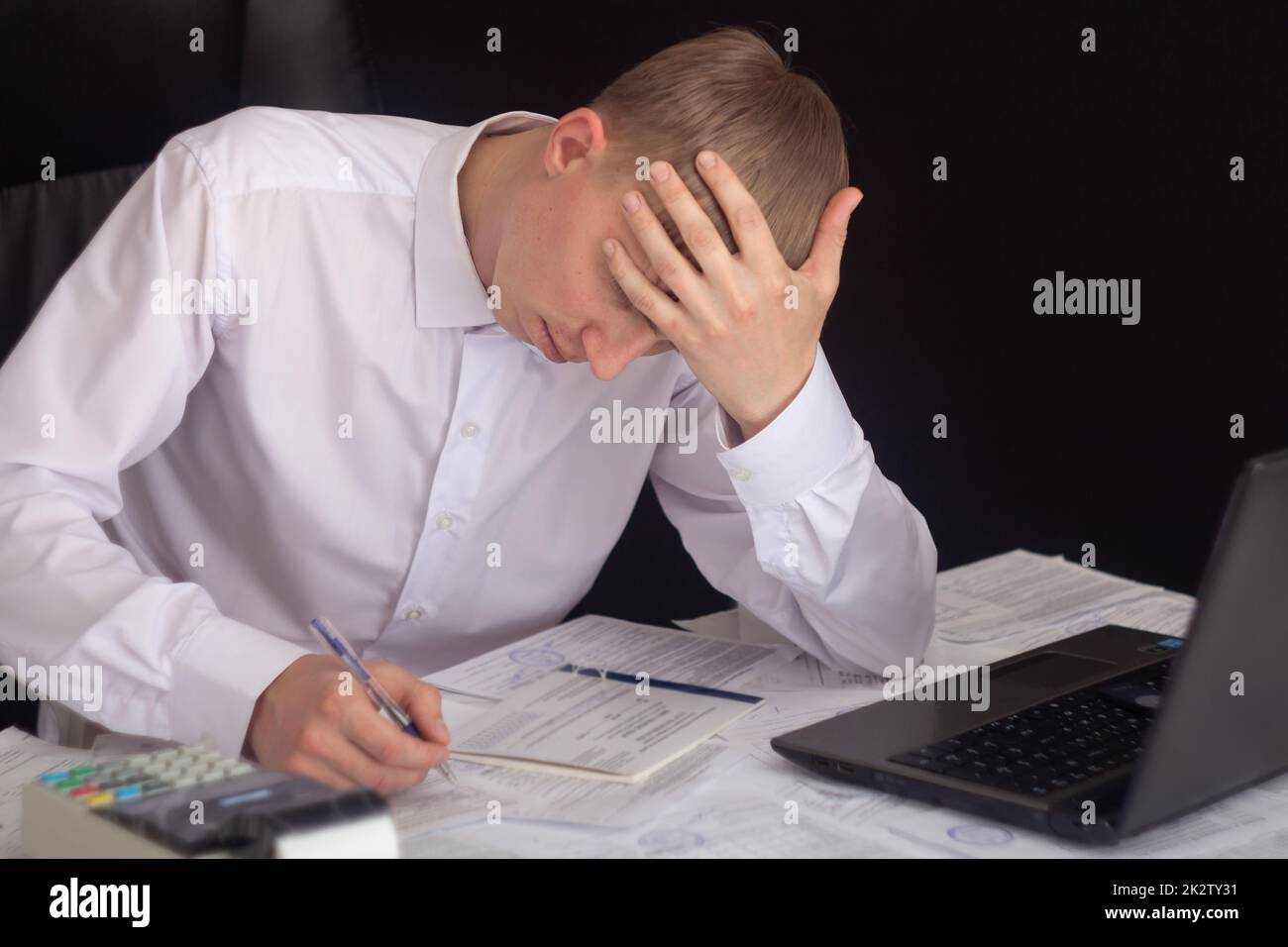 Un homme d'affaires travaille avec des actions, des obligations, des obligations, des titres et des documents dans un bureau de nuit. Respect des obligations de travailler avec des documents au bureau. Employé à un ordinateur portable au bureau. Banque D'Images