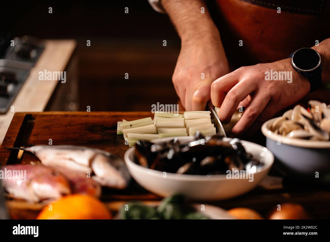 Faire cuire le céleri sur la planche à découper entourée d'une variété d'ingrédients.Mollusques frais crevettes en coquille de poisson.Cuisiner des fruits de mer. Banque D'Images