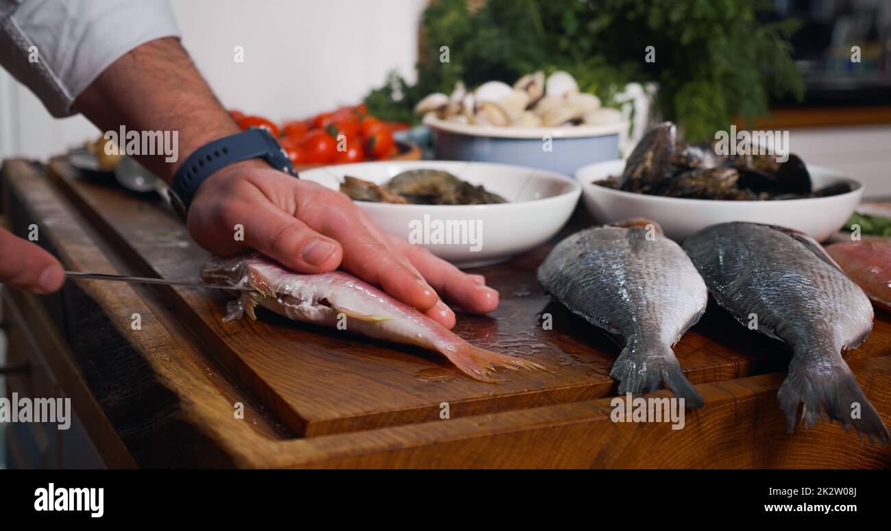 Nettoyage du poisson avant cuisson. Fruits de mer sur un chipper en bois Banque D'Images