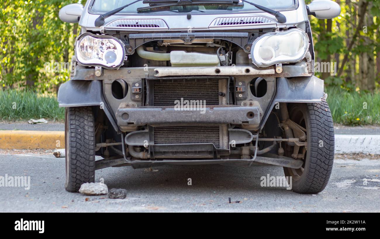 Une petite voiture cassée après un accident de la circulation dans le parking d'un poste de réparation dans la rue. Carrosserie de la voiture endommagée à l'extérieur de l'atelier. Vente de voitures d'assurance aux enchères. Ukraine, Irpen - 12 mai 2022. Banque D'Images