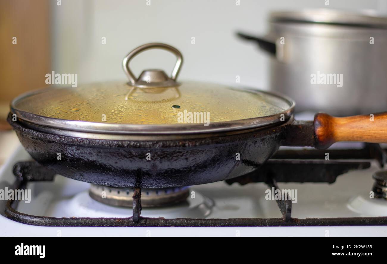 Rôtir les pommes de terre fraîches dans une poêle en fonte avec de l'huile de tournesol. Une vue sur une cuisinière avec une poêle remplie de pommes de terre frites dorées dans une vraie cuisine. Aliments cuits dans une poêle maison. Banque D'Images