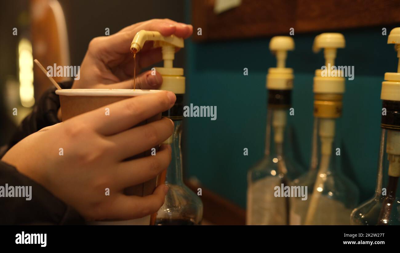 Les femmes ajoutent à la main du sirop de caramel au sirop de noisette pour les noix de café comme le sirop café avec le sirop Banque D'Images