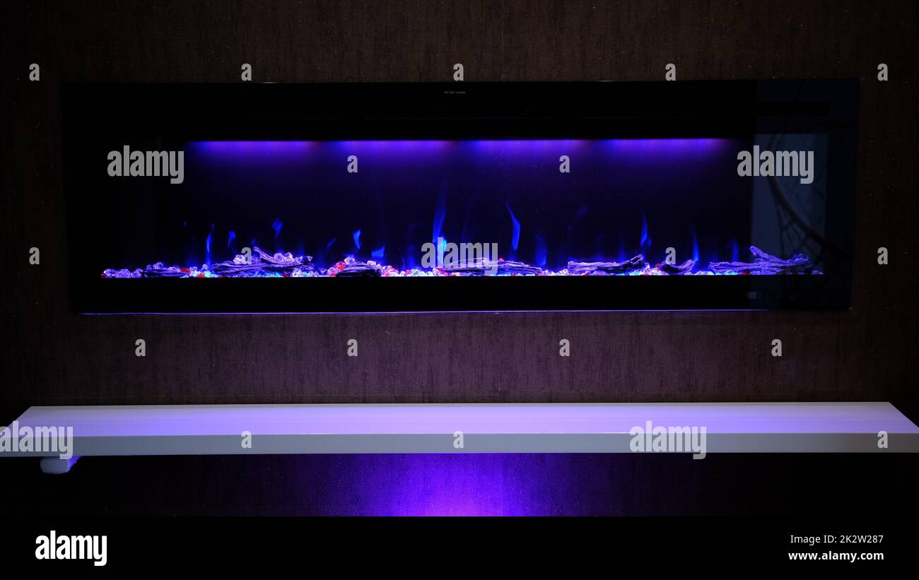 vue sur cheminée électrique avec flamme artificielle étincelante, décor pour l'intérieur, flamme bleue sur cristaux Banque D'Images