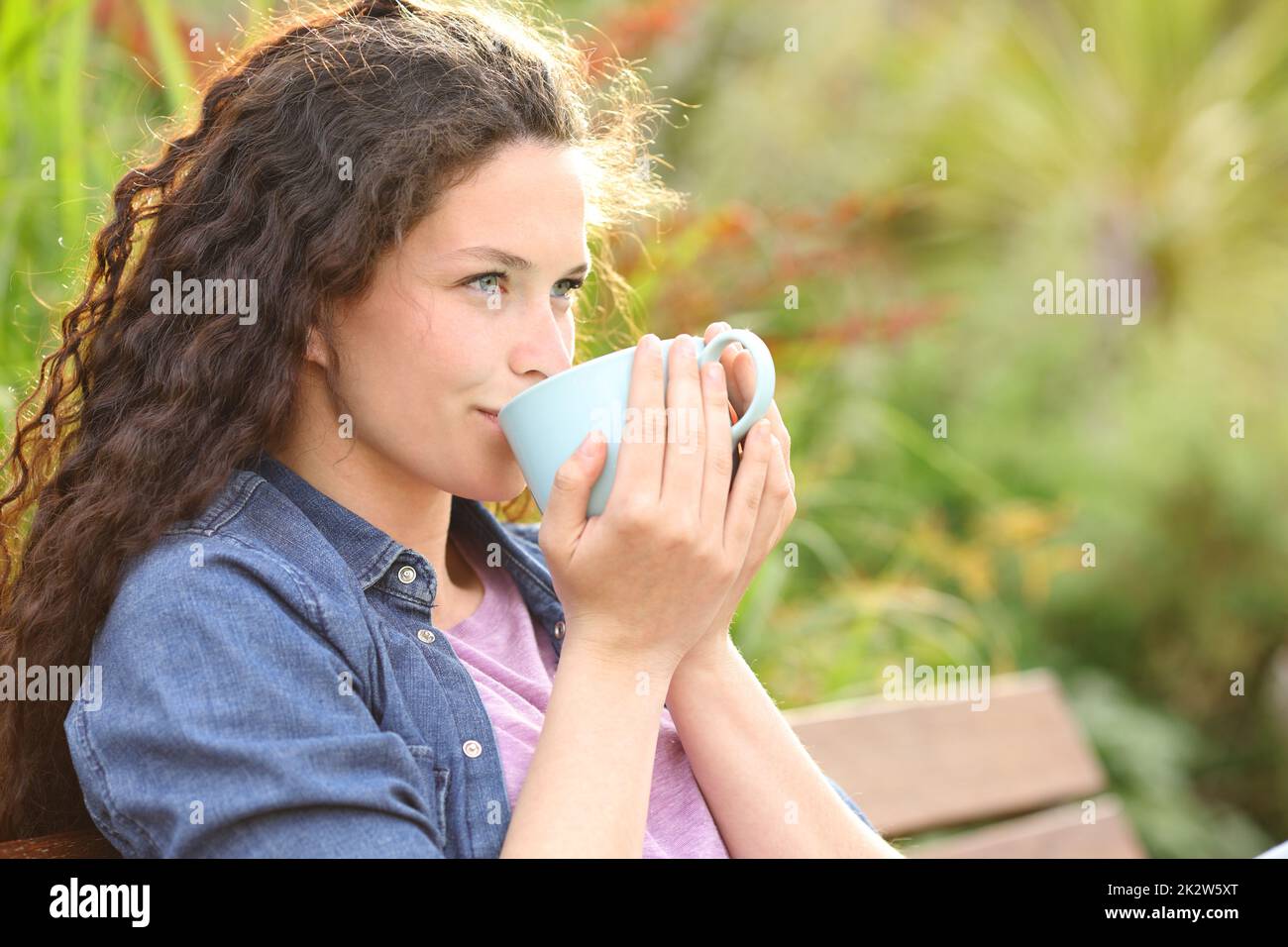 Femme confiante qui boit du café en regardant loin dans un parc Banque D'Images