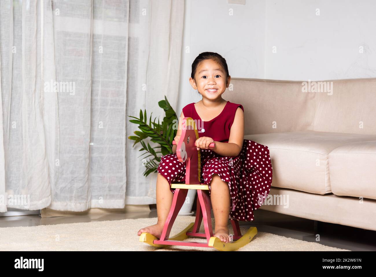 Asiatique mignon petite fille balançant cheval jouet Banque D'Images