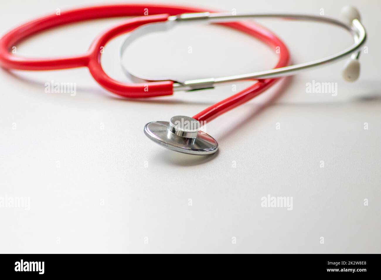 Stéthoscope rouge dans le bureau des médecins pour un examen cardio professionnel et un contrôle du pouls cardiaque sain par un cardiologue dans la salle de traitement clinique sur le bureau blanc comme équipement médical pour mesurer les params du corps Banque D'Images