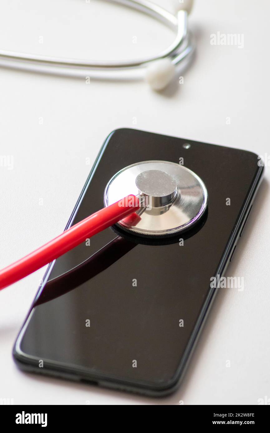 Le stéthoscope rouge sur smartphone noir représente les dossiers médicaux et les dossiers médicaux numériques avec des appareils mobiles pour les médecins numériques et des traitements diagnostiques numériques avec des équipements et technologies modernes Banque D'Images