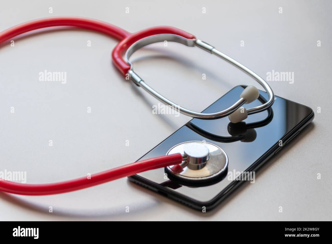Le stéthoscope rouge sur smartphone noir représente les dossiers médicaux et les dossiers médicaux numériques avec des appareils mobiles pour les médecins numériques et des traitements diagnostiques numériques avec des équipements et technologies modernes Banque D'Images