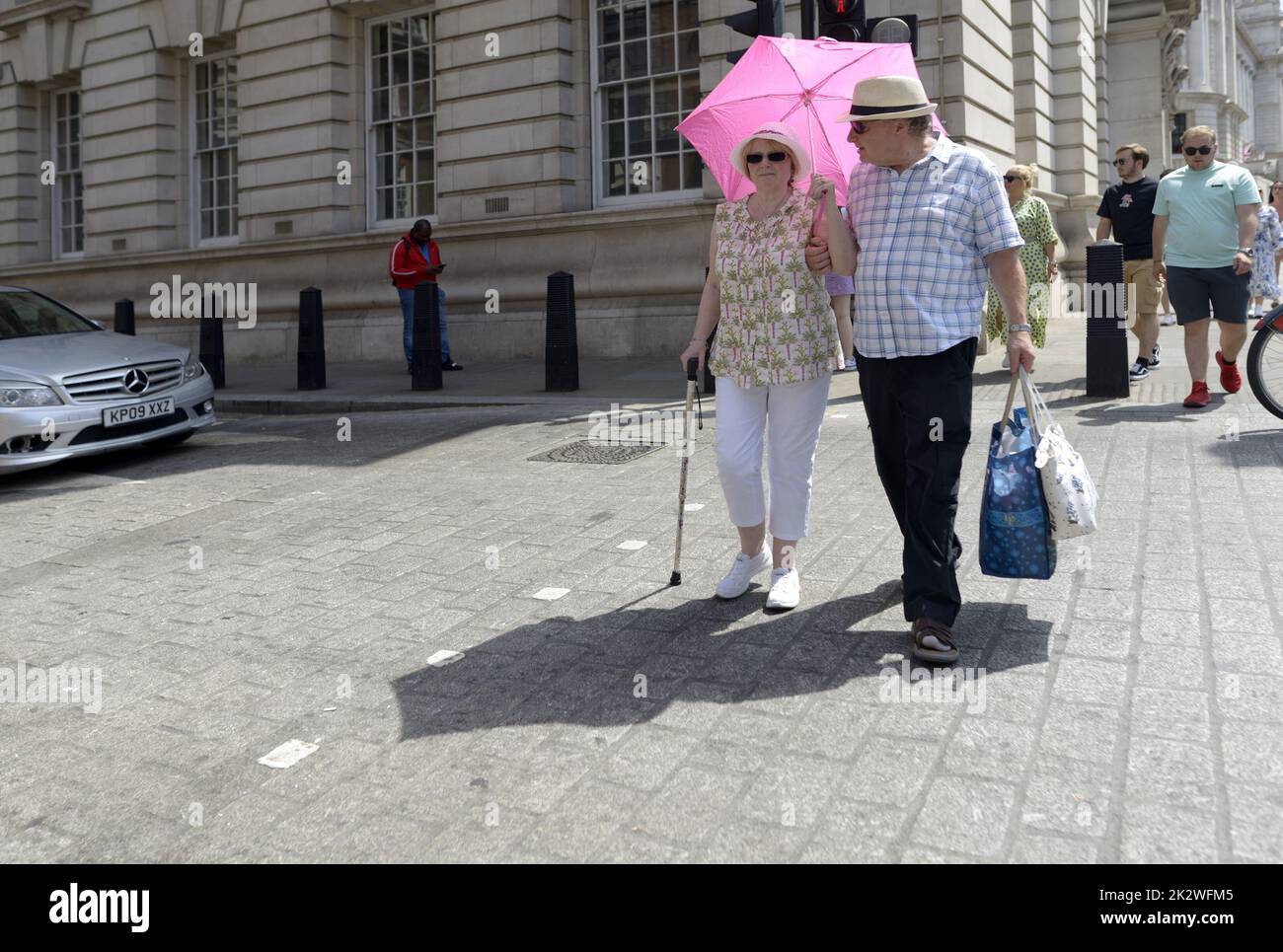 Londres, Angleterre, Royaume-Uni. Couple avec un parapluie par une chaude journée ensoleillée Banque D'Images