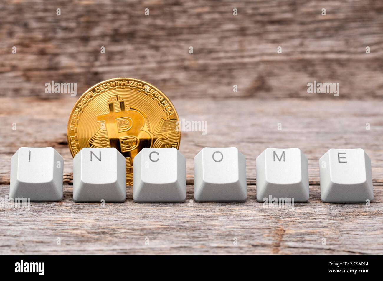 La pièce de monnaie en bitcoin et les touches du clavier de l'ordinateur sont disposées pour épeler LE mot DE REVENU Banque D'Images